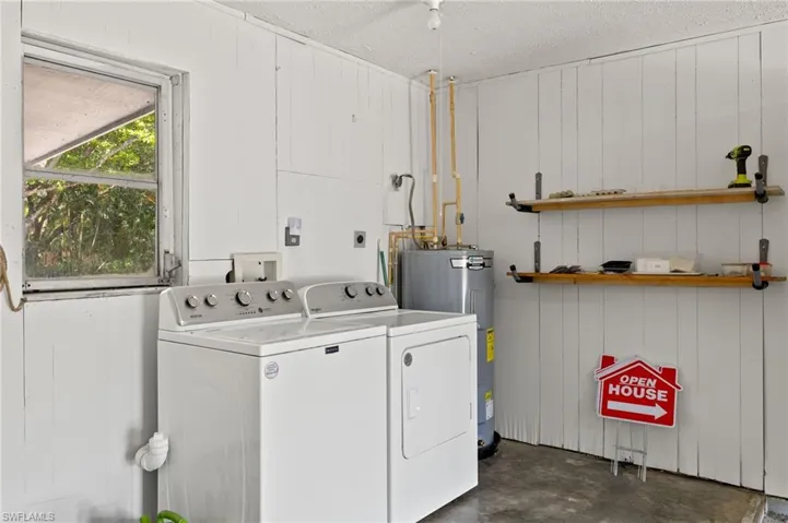 Laundry area featuring washer and dryer, water heater, a textured ceiling, and hookup for a washing machine