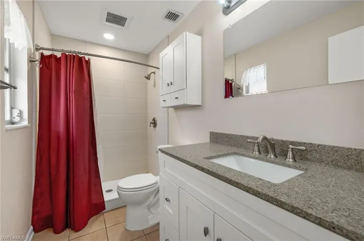 Bathroom with tile flooring, oversized vanity, toilet, and a shower with shower curtain