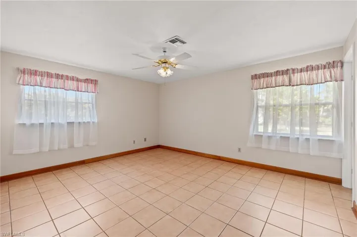 Tiled empty room with plenty of natural light and ceiling fan
