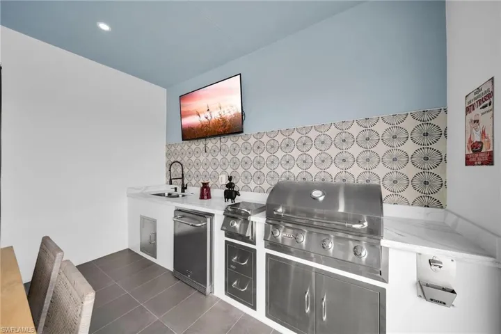 Kitchen featuring light stone counters, sink, dark tile flooring, and fridge