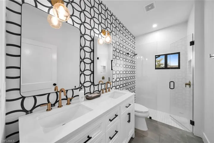Bathroom with tile flooring, an enclosed shower, double vanity, and toilet