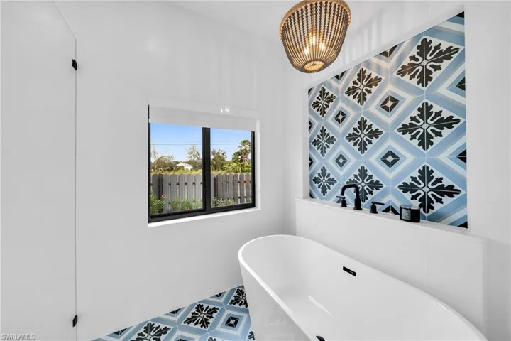 Bathroom with a bathtub, tile flooring, and a chandelier