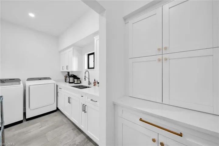 Washroom featuring sink, light hardwood / wood-style flooring, and washing machine and clothes dryer