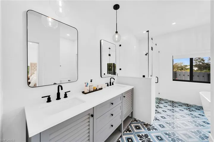 Bathroom featuring tile flooring, a washtub, dual sinks, and vanity with extensive cabinet space