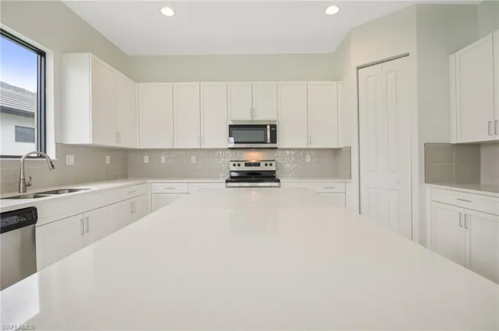 Kitchen with white cabinetry, backsplash, and stainless steel appliances