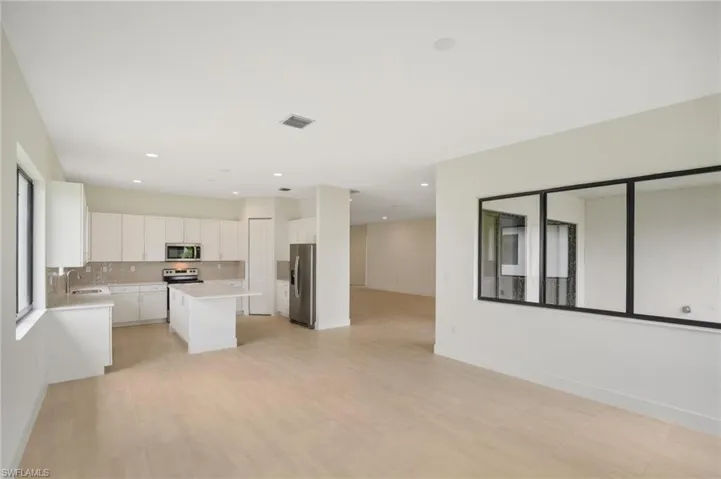 Kitchen with a center island, white cabinetry, appliances with stainless steel finishes, backsplash, and sink