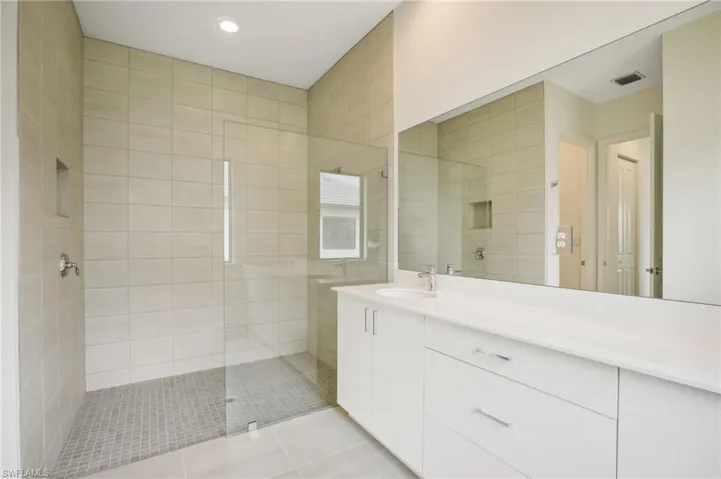 Bathroom with vanity with extensive cabinet space, an enclosed shower, and tile floors
