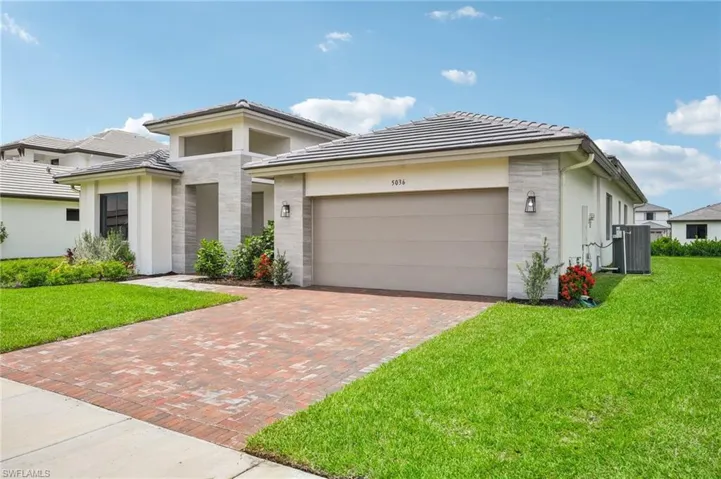 Prairie-style home with a garage, a front lawn, and central AC unit