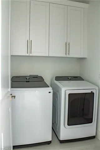 Washroom featuring cabinet space and separate washer and dryer