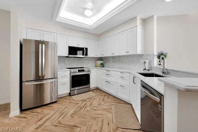 Kitchen featuring sink, white cabinetry, stainless steel appliances, and tasteful backsplash