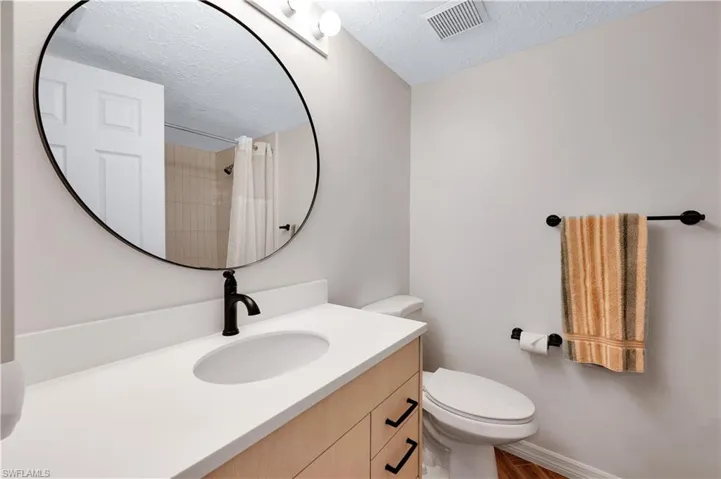 Bathroom featuring a shower with curtain, vanity, a textured ceiling, hardwood / wood-style floors, and toilet