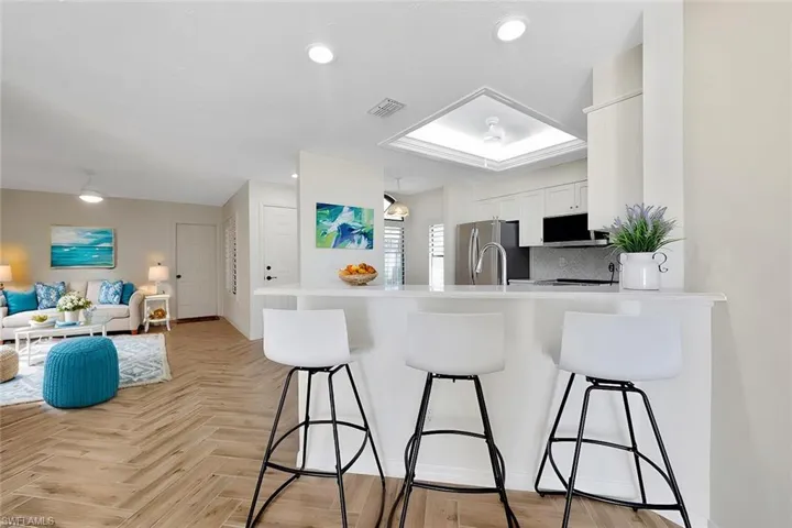 Kitchen featuring white cabinetry, kitchen peninsula, stainless steel appliances, and light parquet floors