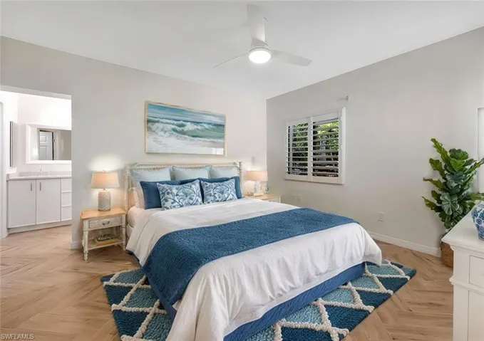 Bedroom with ceiling fan, ensuite bath, and light parquet floors