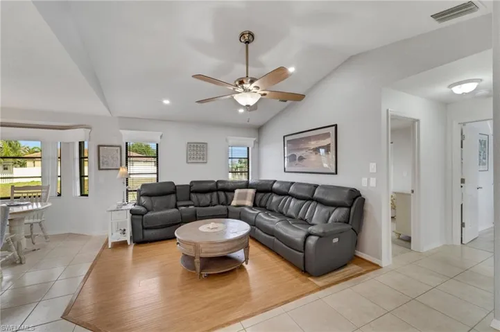 Living room featuring lofted ceiling, ceiling fan, and light hardwood / wood-style flooring
