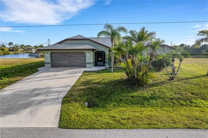 View of front facade with a front yard, a garage, and a water view