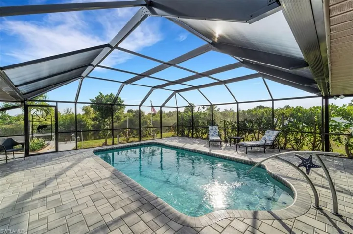 View of pool with glass enclosure and a patio area