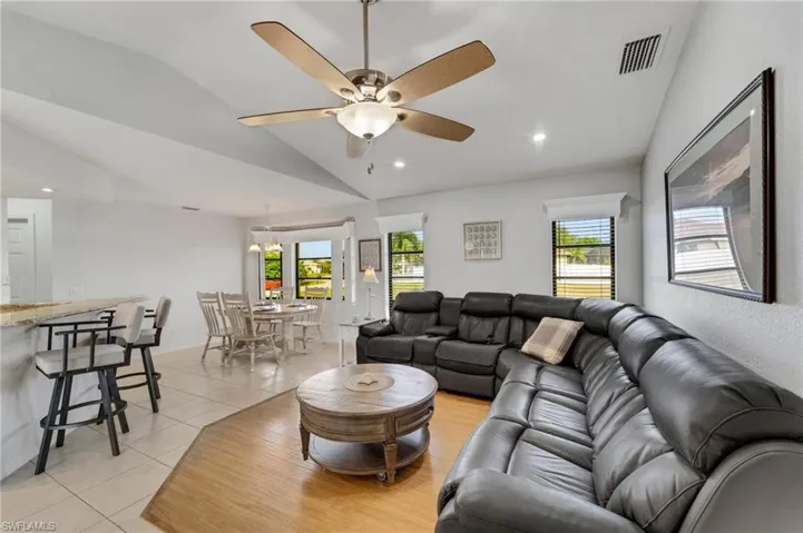 Living room featuring light tile floors, ceiling fan, and vaulted ceiling