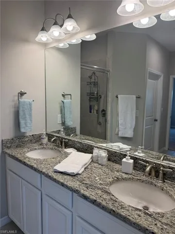Double vanity featuring granite countertops, two undermount sinks, and white cabinetry