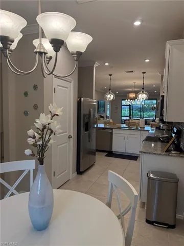 Kitchen featuring stainless steel appliances, white cabinetry, granite countertops, and tile flooring