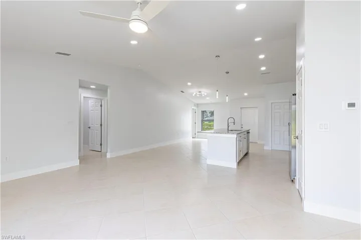 Unfurnished living room featuring light tile patterned flooring, sink, and ceiling fan