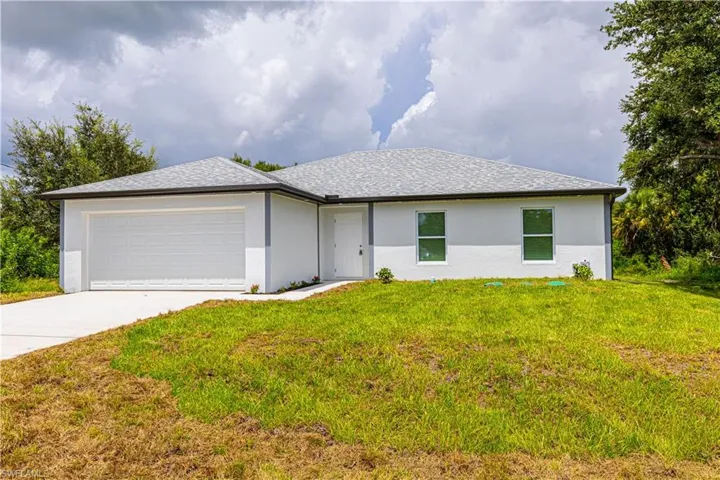 Single story home with a garage and a front lawn
