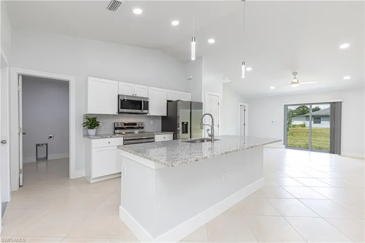 Kitchen featuring stainless steel appliances, white cabinetry, sink, ceiling fan, and pendant lighting