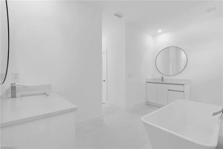 Bathroom featuring two vanities, a freestanding bath, and recessed lighting