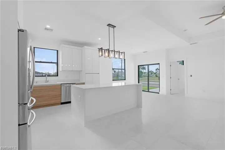 Dual tone kitchen featuring a kitchen island, stainless steel appliances, two tone cabinets, modern cabinets, and ceiling fan