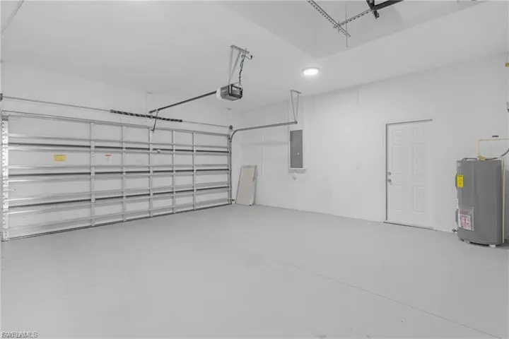 Garage featuring water heater, electric panel, and a garage door opener