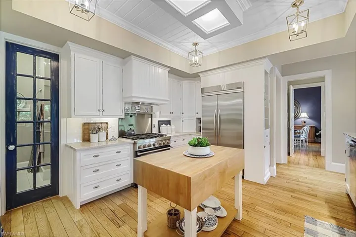 Kitchen with white cabinets, light wood-type flooring, hanging light fixtures, and premium appliances