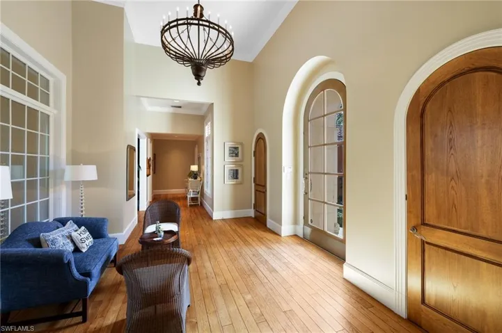 Foyer entrance featuring high vaulted ceiling, light wood-type flooring, and a chandelier