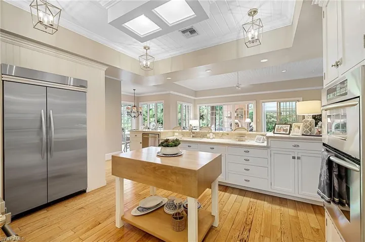 Kitchen with a kitchen island, white cabinetry, light hardwood / wood-style floors, and stainless steel appliances