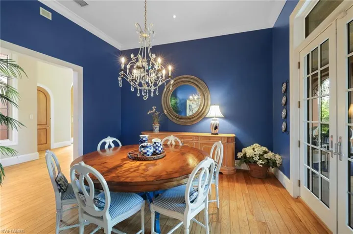 Dining area with french doors, light hardwood / wood-style flooring, a notable chandelier, and crown molding