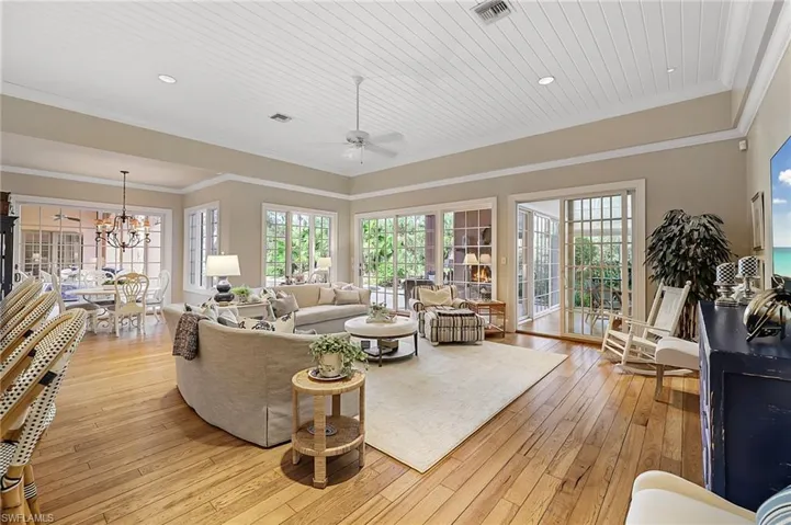 Living room featuring ornamental molding, ceiling fan with notable chandelier, light hardwood / wood-style flooring, and wood ceiling