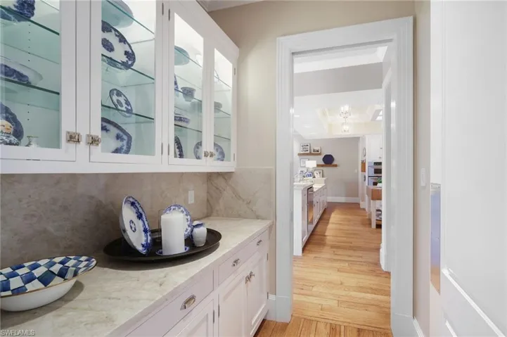 Bar with light stone countertops, light hardwood / wood-style floors, and white cabinetry