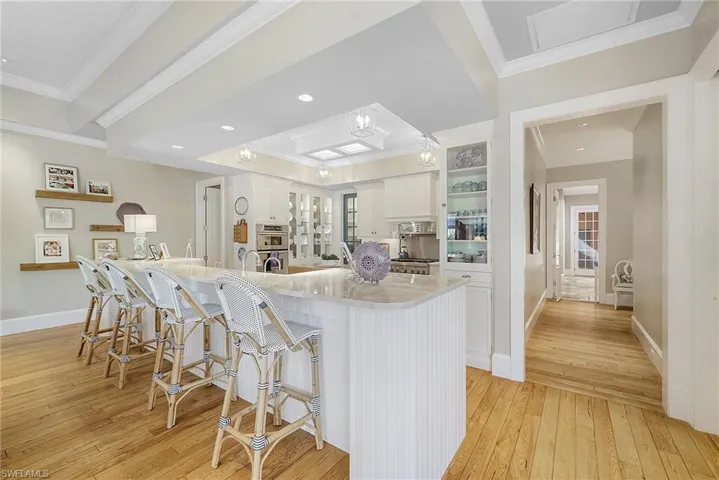 Kitchen with white cabinetry, light wood-type flooring, double oven, and ornamental molding