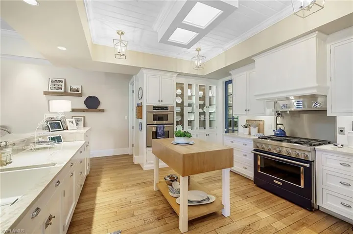 Kitchen with white cabinets, light hardwood / wood-style floors, light stone counters, and appliances with stainless steel finishes