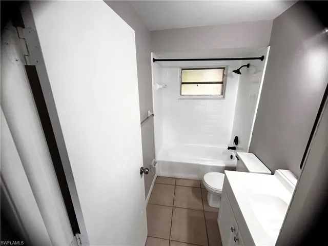 Bathroom featuring vanity, shower / tub combination, and tile patterned flooring