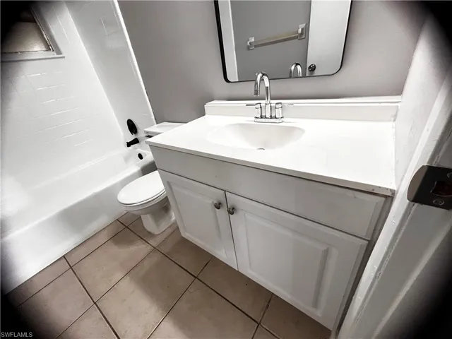 Full bath featuring vanity, light tile patterned floors, and shower / tub combination