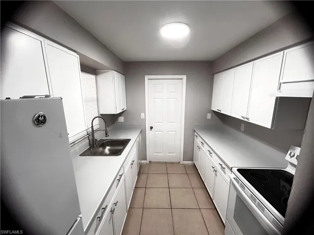 Kitchen with stainless steel fridge, white electric range oven, and white cabinetry