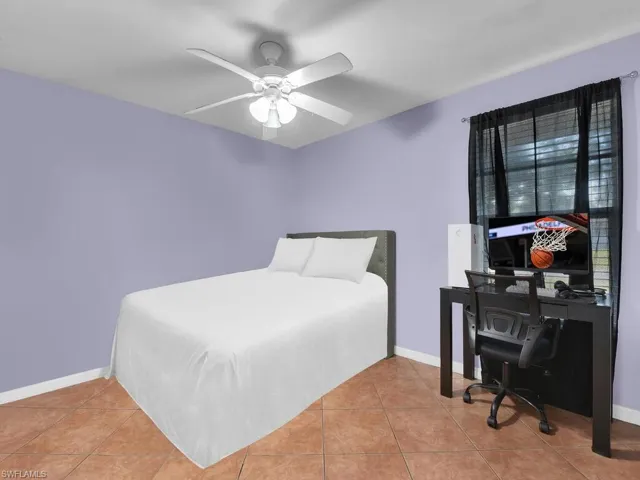 Bedroom with an office area, ceiling fan, and light tile patterned floors