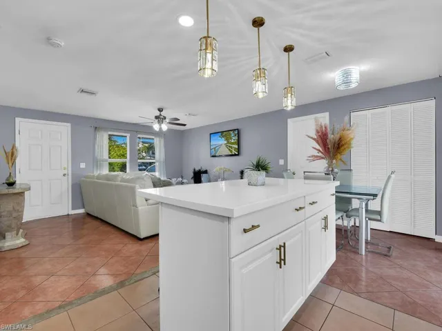 Kitchen featuring white cabinets, light tile patterned floors, a kitchen island, and open floor plan