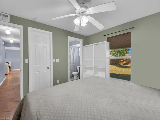 Bedroom featuring tile patterned flooring, a ceiling fan, and connected bathroom