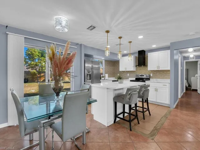 Kitchen with white cabinets, a kitchen island, hanging light fixtures, a breakfast bar, and light tile patterned floors