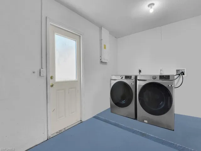 Laundry room with separate washer and dryer, electric panel, and finished concrete flooring