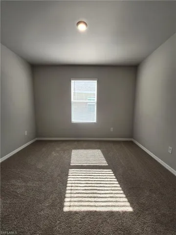Empty room featuring dark colored carpet