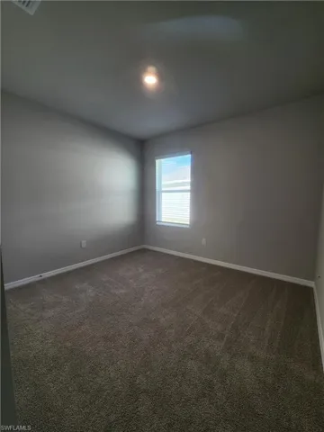 Empty room featuring dark carpet and baseboards