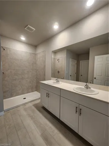 Bathroom with a stall shower, double vanity, and wood finish floors