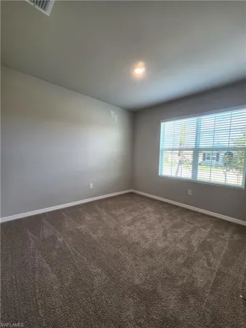 Spare room featuring dark carpet and baseboards