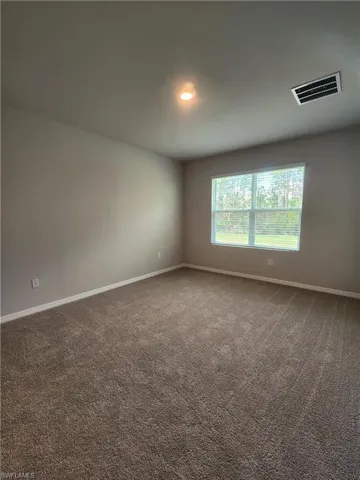 Spare room with baseboards and dark colored carpet